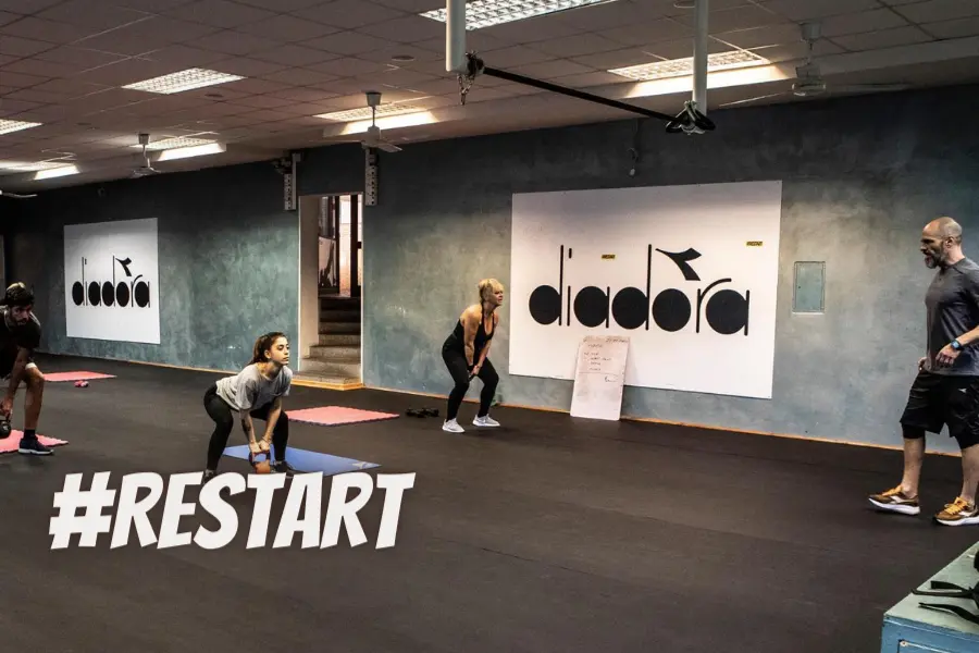 Persone che si allenano in palestra con istruttore durante allenamento fitness in sicurezza