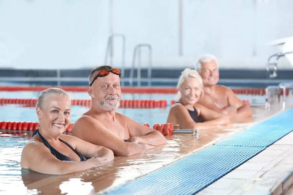 Gruppo di anziani in piscina durante attività di nuoto per benessere e salute
