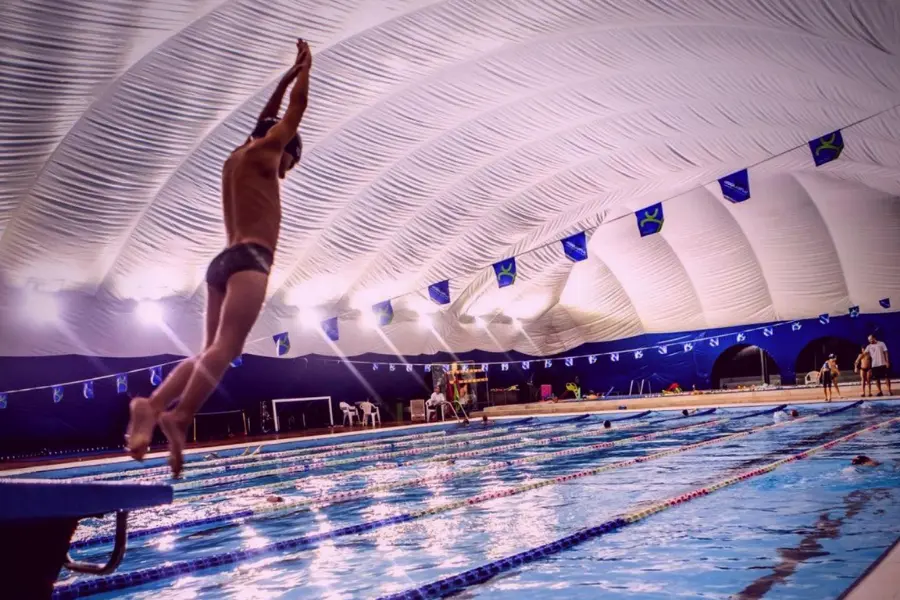 Nuotatore si tuffa in piscina coperta durante allenamento di nuoto in corsia