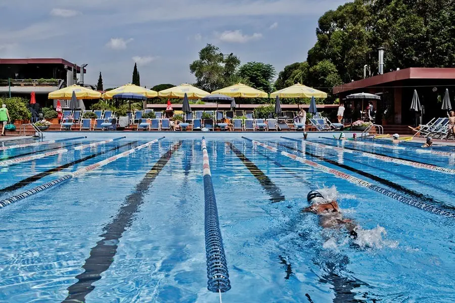 Nuotatore in piscina estiva a Roma durante allenamento in corsia all’aperto