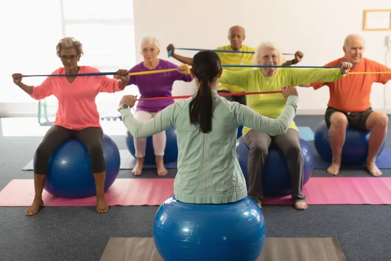 Gruppo di anziani durante esercizi con elastici in palestra per migliorare forza e mobilità