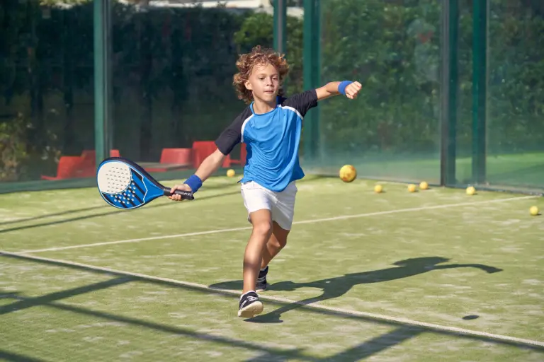 Bambino durante allenamento di padel mentre colpisce la palla per migliorare coordinazione e riflessi