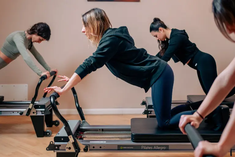 Donna durante esercizio su pilates reformer per core stability ed equilibrio in palestra