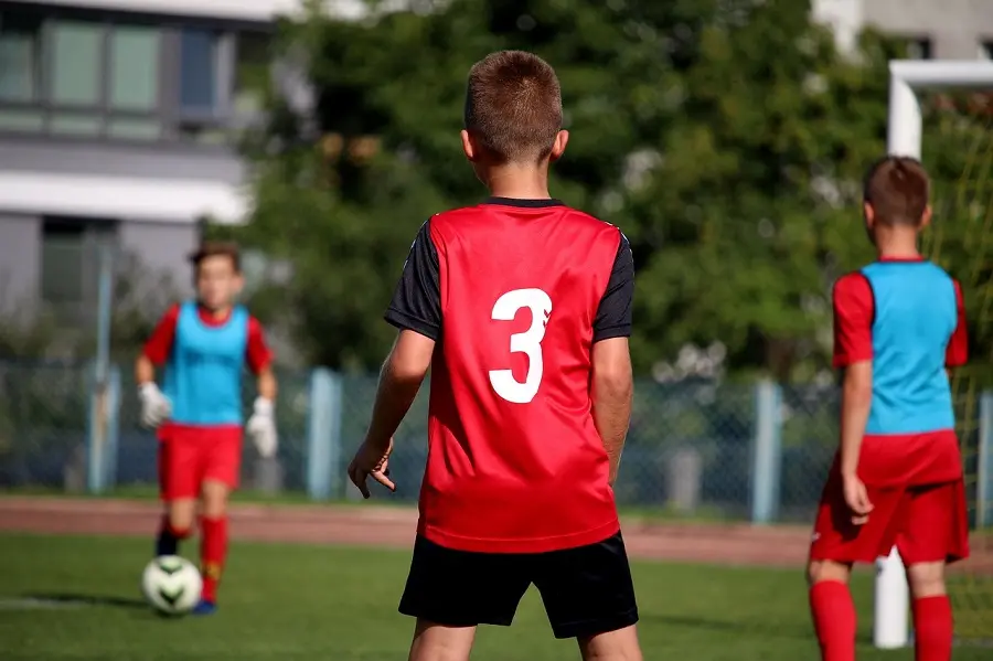 Bambini che giocano a calcio durante allenamento sportivo utile alla crescita fisica e sociale